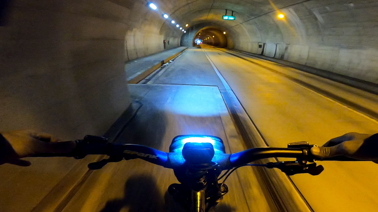 A dark cycle path showing twilight hazards like concrete barriers and rough ground