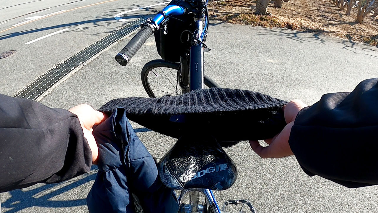 A bizarre makeshift saddle cover formed from a black knit beanie and puffy down hood