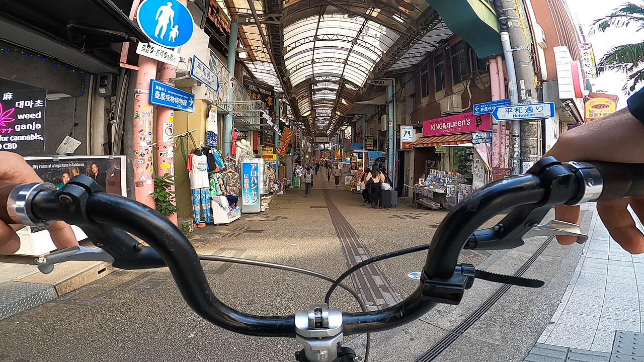 Kokusai-dori covered shopping arcade with colorful storefronts, neon signs, and crowds of shoppers