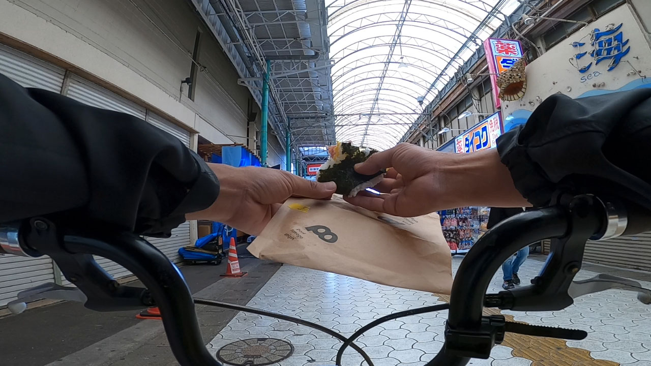 Pota-ma - triangular rice ball wrapped in plastic with visible Spam and egg inside