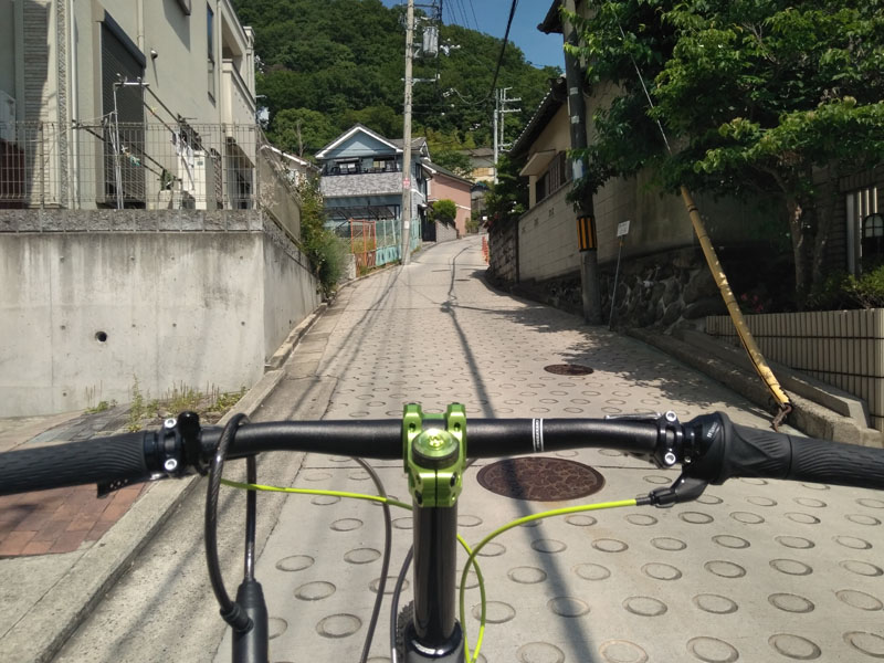 A steep uphill road entering a residential area with circle-patterned concrete